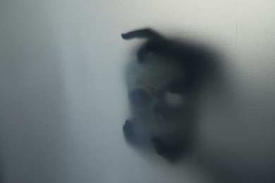 Silhouette of creepy ghost with skull behind cloth, space for text