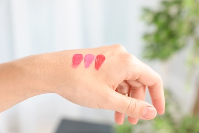 Photo of Woman testing and choosing lip gloss color on hand, closeup