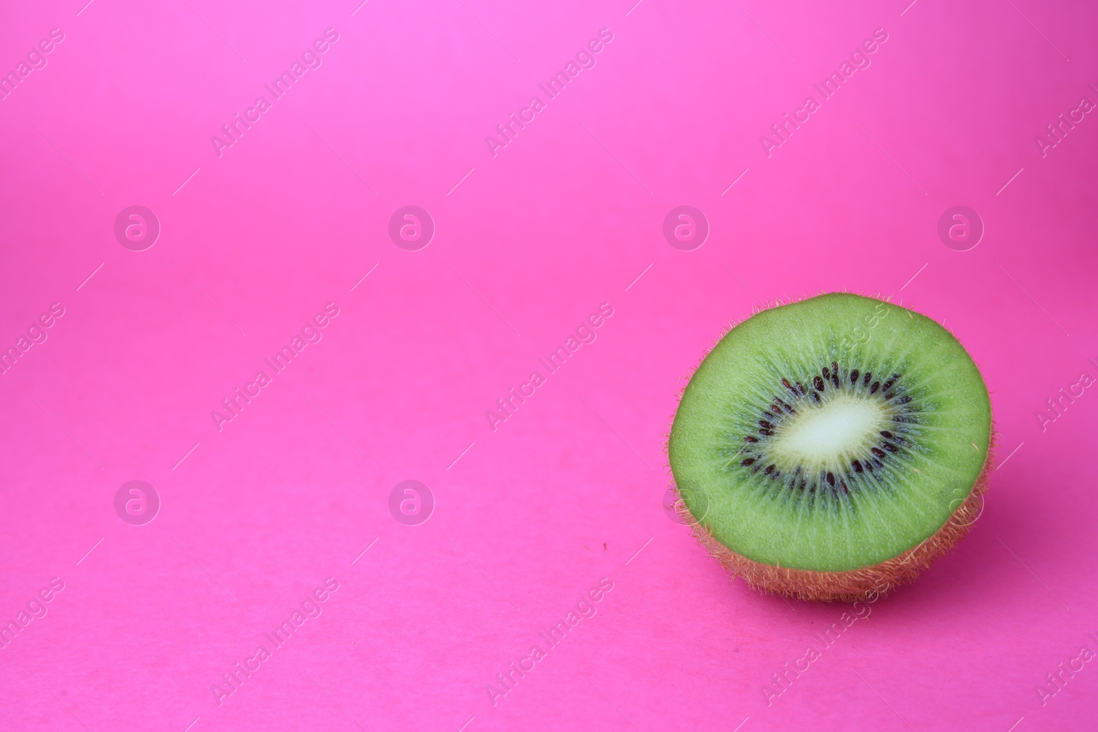 Photo of Cut fresh ripe kiwi on pink background, space for text