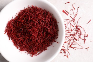 Photo of Aromatic saffron in bowl on light table, top view