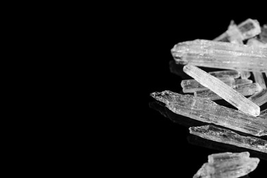 Menthol crystals on black background, closeup. Space for text