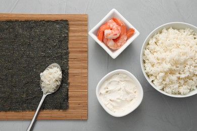 Photo of Cooking sushi. Nori, spoon with rice and other ingredients on grey textured table, flat lay