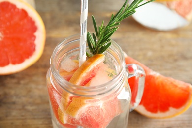 Photo of Mason jar of infused water with grapefruit slices on table, closeup