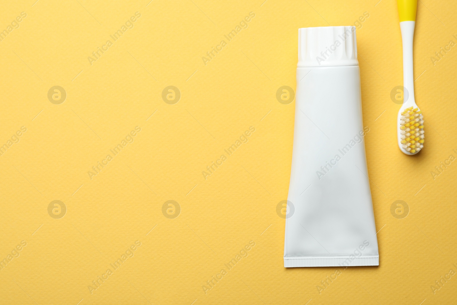 Photo of Blank tube of toothpaste and brush on color background, top view with space for text