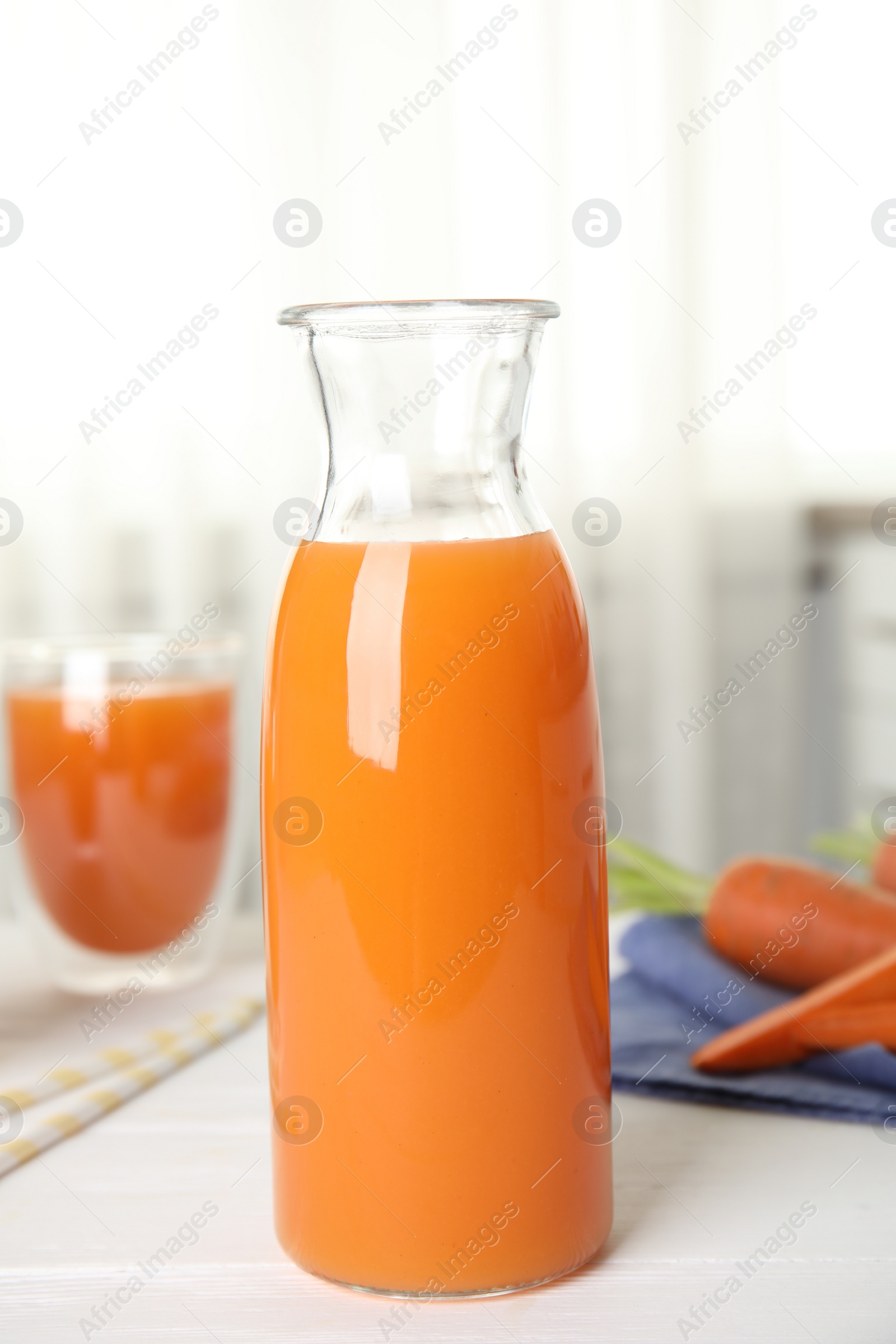 Photo of Freshly made carrot juice on white table