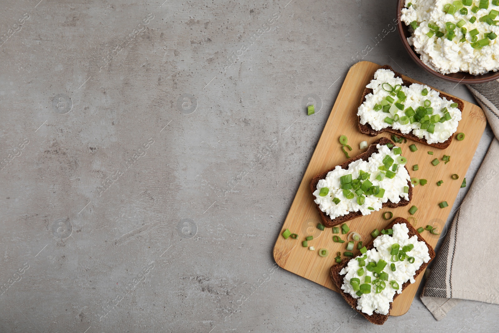 Photo of Bread with cottage cheese and green onion on light grey table, flat lay. Space for text