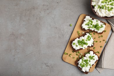 Photo of Bread with cottage cheese and green onion on light grey table, flat lay. Space for text