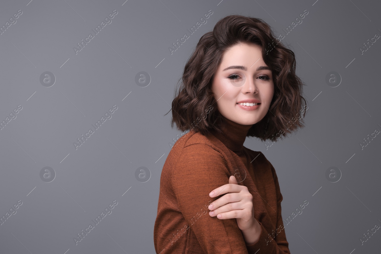 Photo of Portrait of beautiful young woman with wavy hairstyle on grey background. Space for text