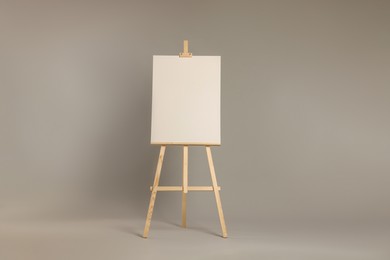 Photo of Wooden easel with blank canvas on grey background