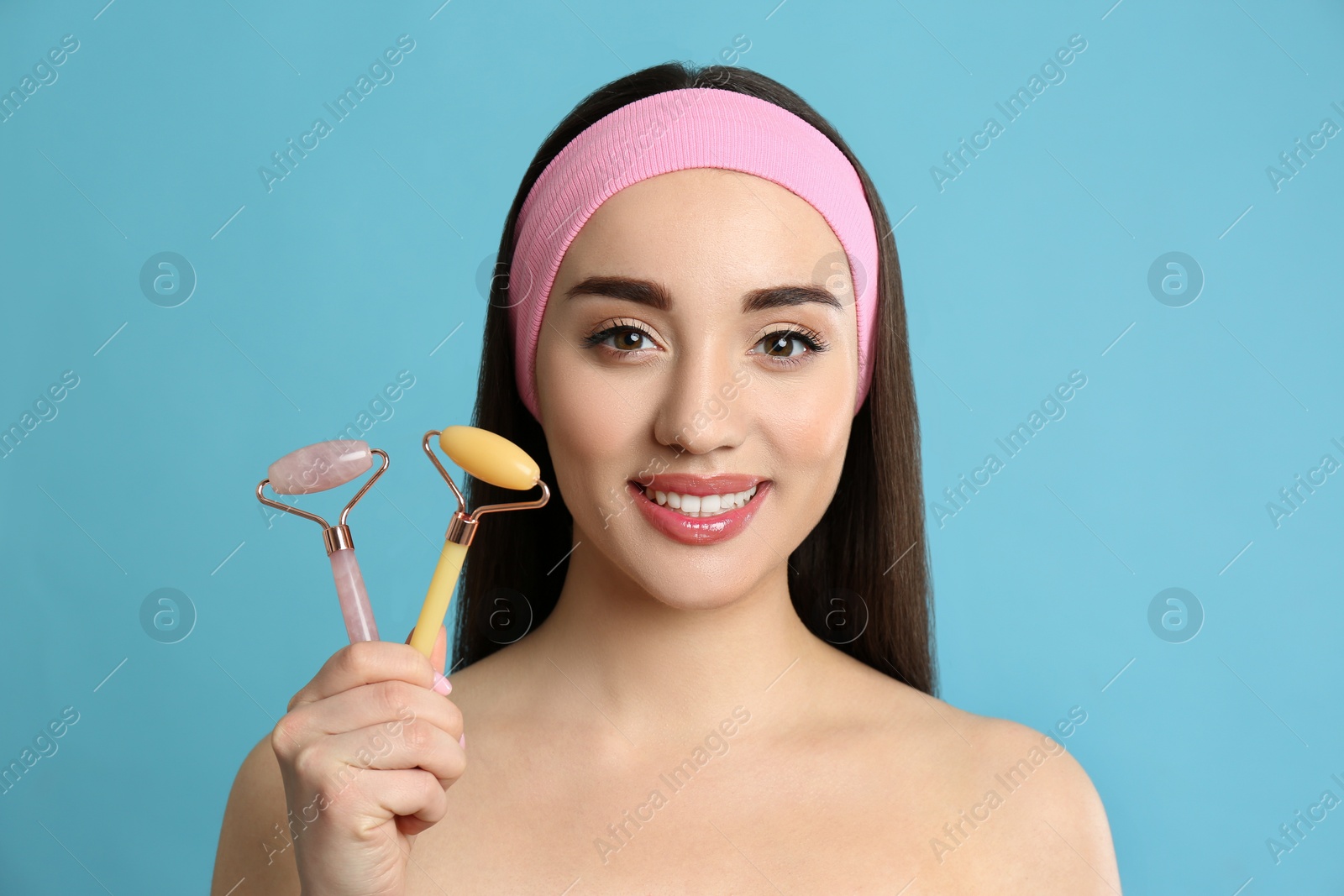 Photo of Woman with natural face rollers on light blue background