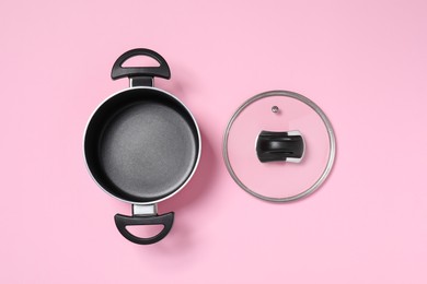 Empty pot and glass lid on pink background, flat lay