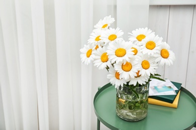 Photo of Vase with beautiful chamomile flowers on table