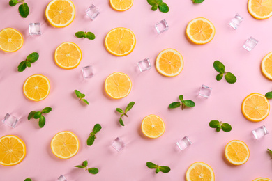 Lemonade layout with juicy lemon slices, mint and ice cubes on pink background, top view