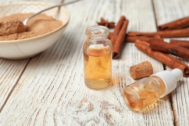 Photo of Bottles with cinnamon essential oil on wooden table