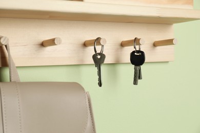 Photo of Wooden hanger for keys on light green wall