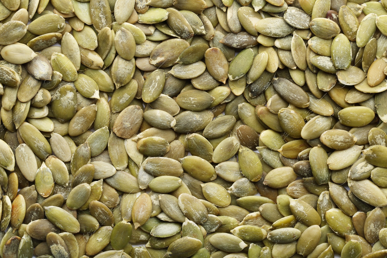 Photo of Shelled raw pumpkin seeds as background, top view