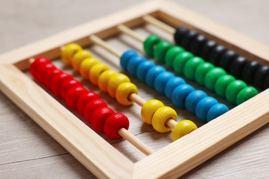 Photo of Colorful toy abacus on white wooden table, closeup. Funny math game