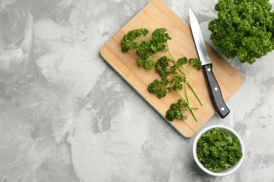 Photo of Fresh curly parsley, cutting board and knife on grey table, flat lay. Space for text