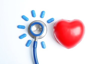 Photo of Flat lay composition with stethoscope, pills and heart model on light background. Medical equipment