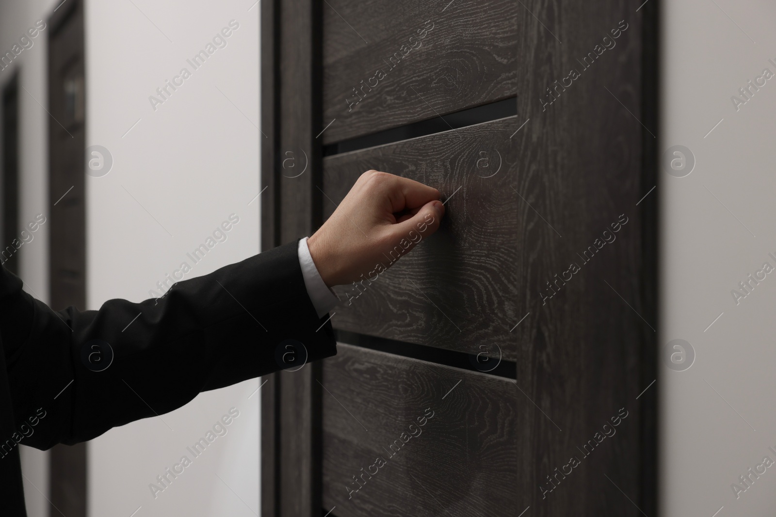 Photo of Collector knocking on door indoors, closeup view