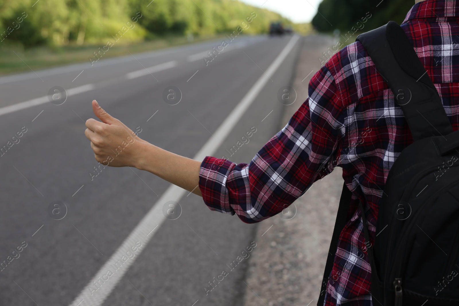 Photo of Woman catching car on road, closeup. Hitchhiking trip