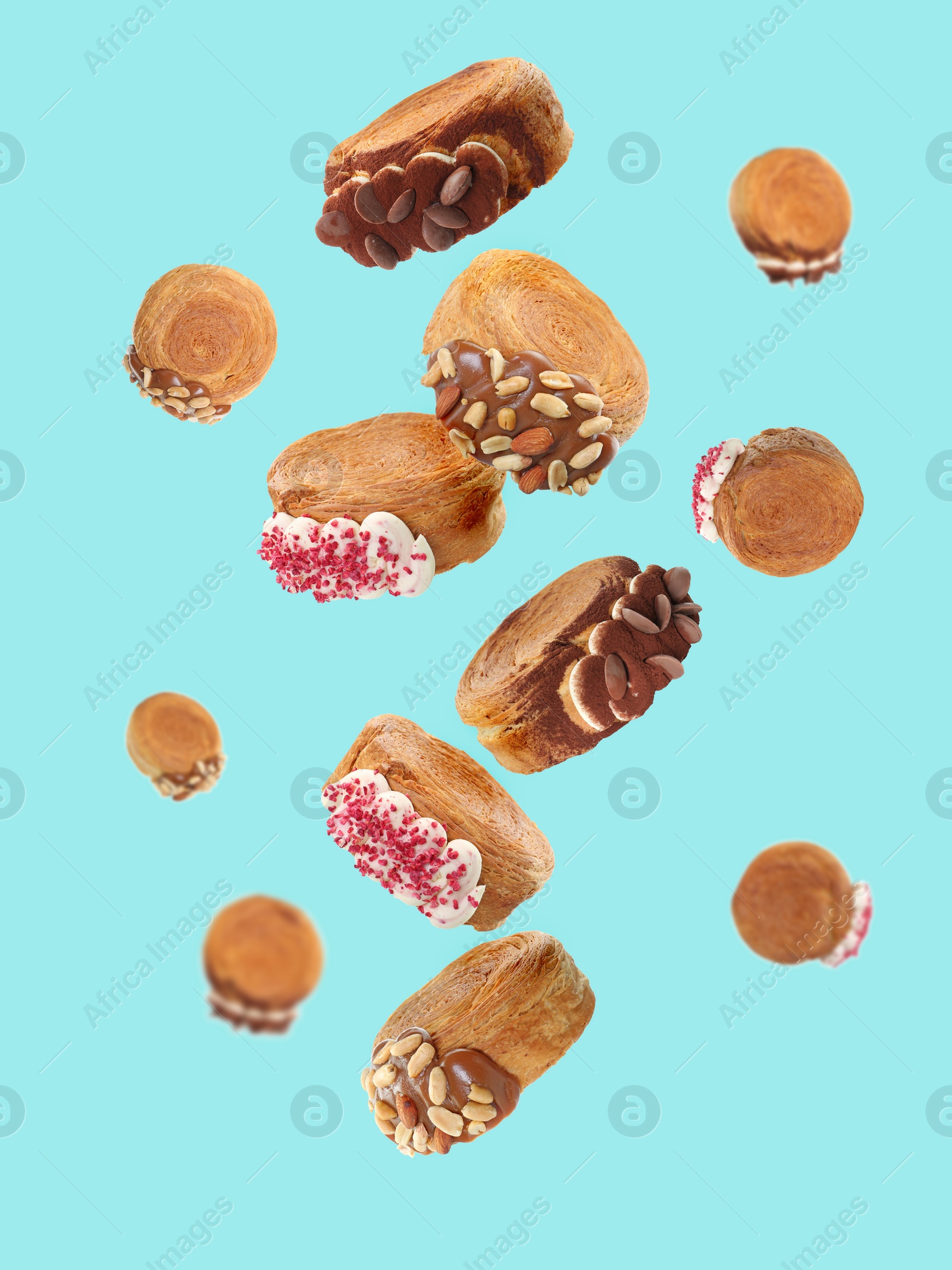 Image of Delicious round croissants in air on light blue background. Puff pastry