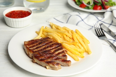 Grilled steak with French fries on white table