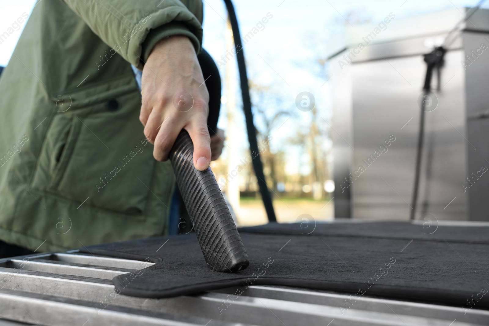 Photo of Man cleaning auto carpets with vacuum cleaner at self-service car wash, closeup