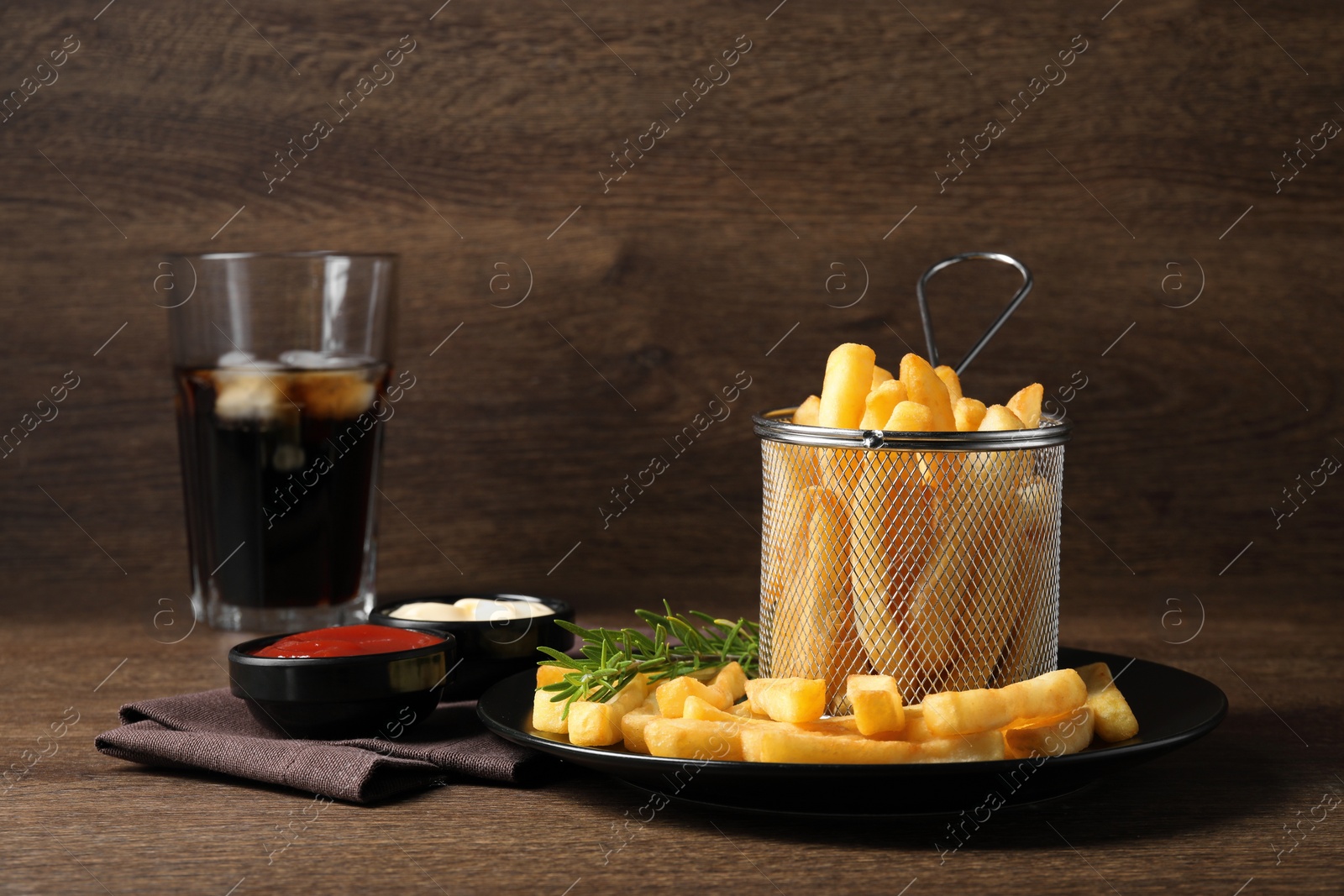 Photo of Delicious French fries served with sauces on wooden table