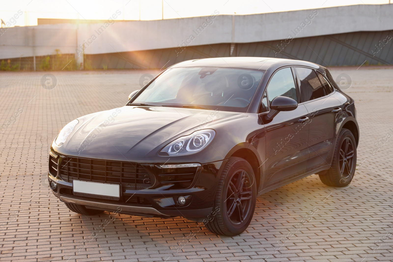 Photo of Modern black car parked on stone pavement outdoors