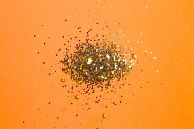 Photo of Shiny bright golden glitter on pale coral background, flat lay