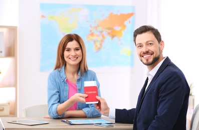 Photo of Male manager giving passport with ticket to client in travel agency