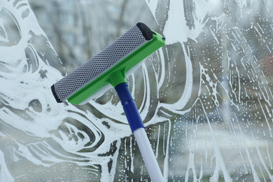 Cleaning window with squeegee indoors. Household chores