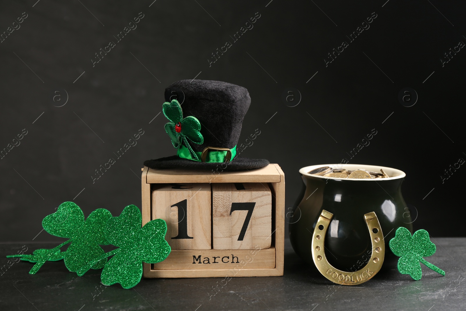 Photo of Leprechaun's hat, block calendar and St. Patrick's day decor on black background