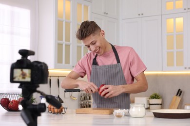 Smiling food blogger cooking while recording video in kitchen