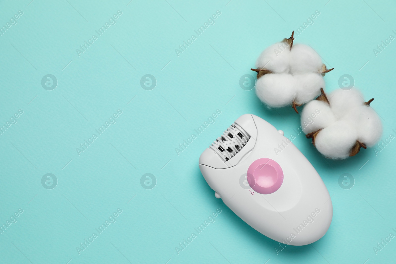 Photo of Modern epilator and fluffy cotton flowers on turquoise background, flat lay. Space for text