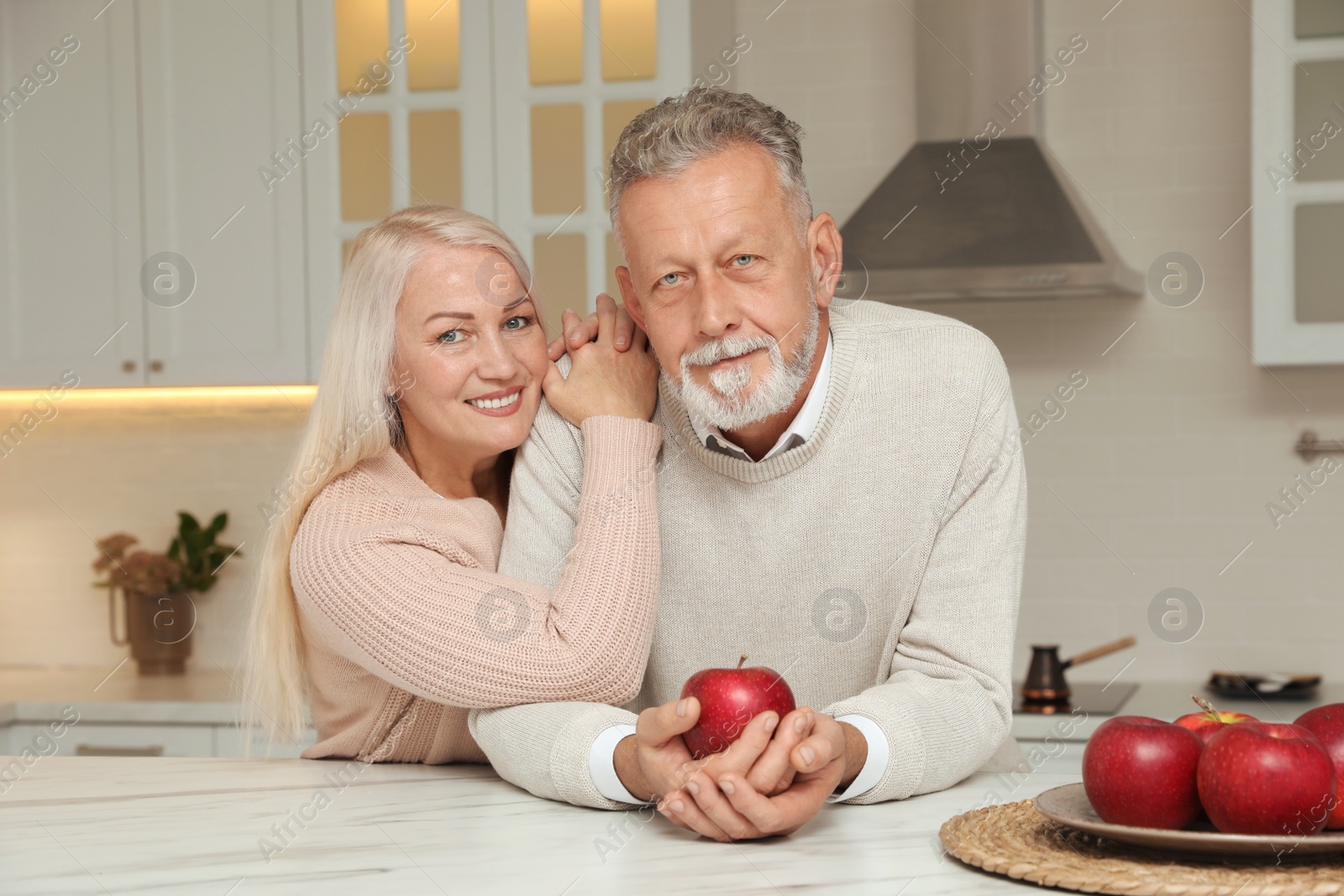 Photo of Happy senior couple at table in kitchen