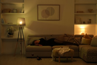 Woman resting on couch in room at night