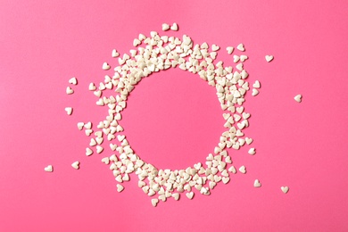Photo of Frame made of white heart shaped sprinkles on pink background, top view. Space for text