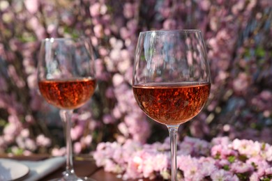 Photo of Glasses of rose wine on table in spring garden