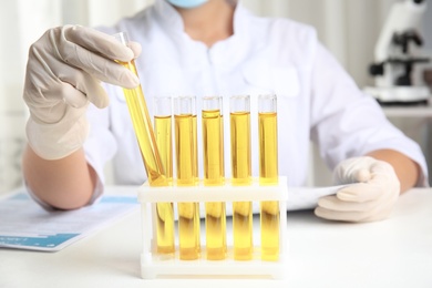 Doctor holding test tube with urine sample for analysis in laboratory, closeup