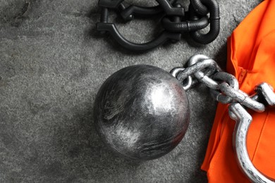 Photo of Prisoner ball with chain and jail clothes on grey table, flat lay