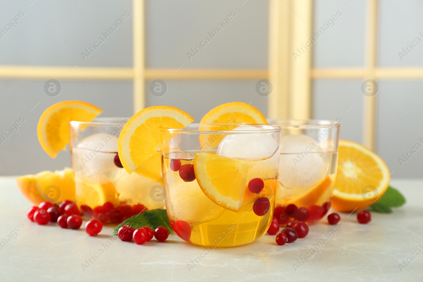 Photo of Delicious cocktails with orange, cranberries and ice balls on light grey marble table