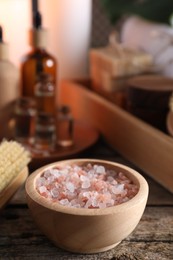 Photo of Spa treatment. Sea salt in bowl on wooden table, space for text