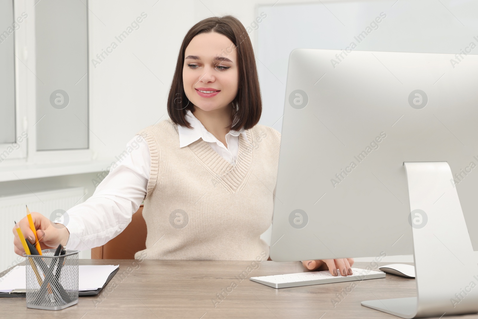 Photo of Happy young intern working at table in modern office