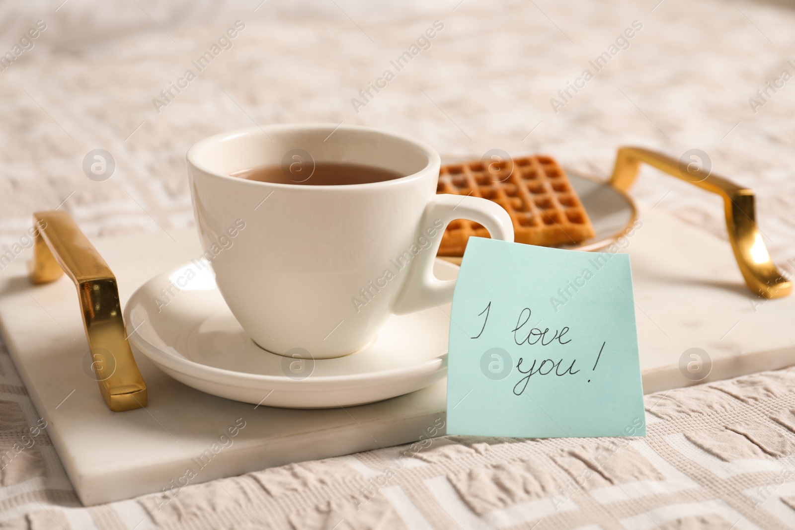 Photo of Paper note I Love You near cup of morning drink and waffle on bed. Romantic breakfast