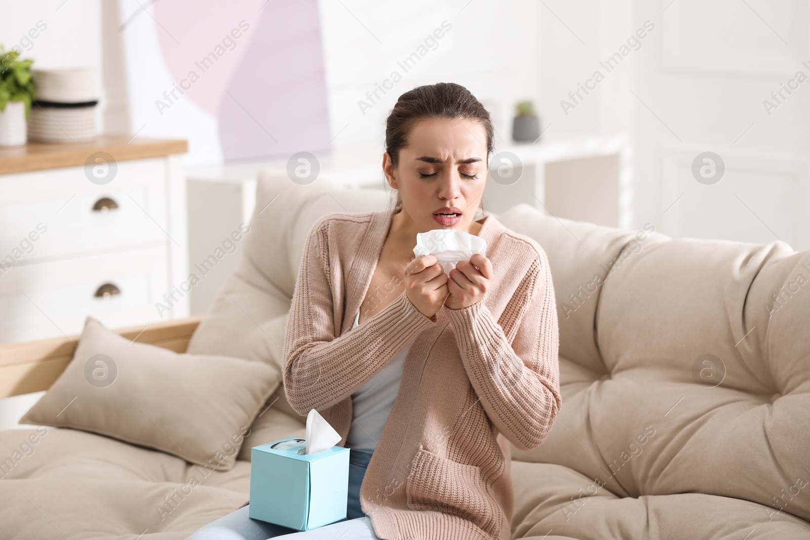 Photo of Young woman suffering from runny nose in living room