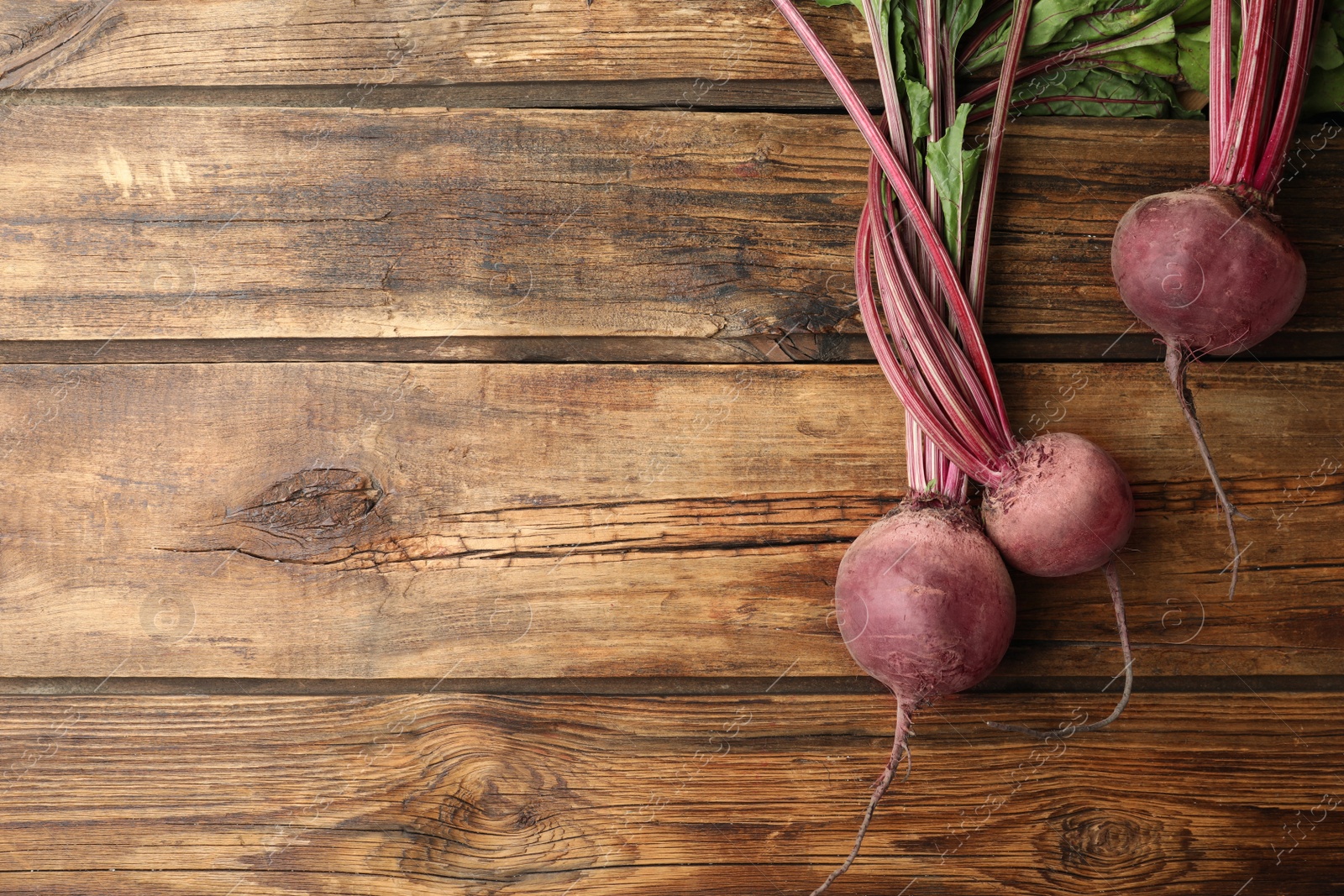 Photo of Raw ripe beets on wooden table, flat lay. Space for text