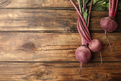 Raw ripe beets on wooden table, flat lay. Space for text