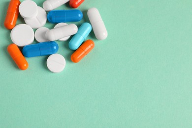 Photo of Pile of colorful pills on green background, above view. Space for text